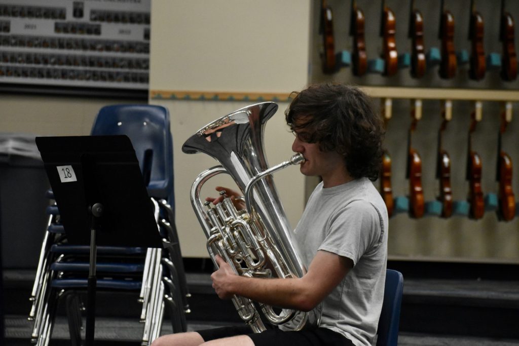 a man sitting down playing a trumpet